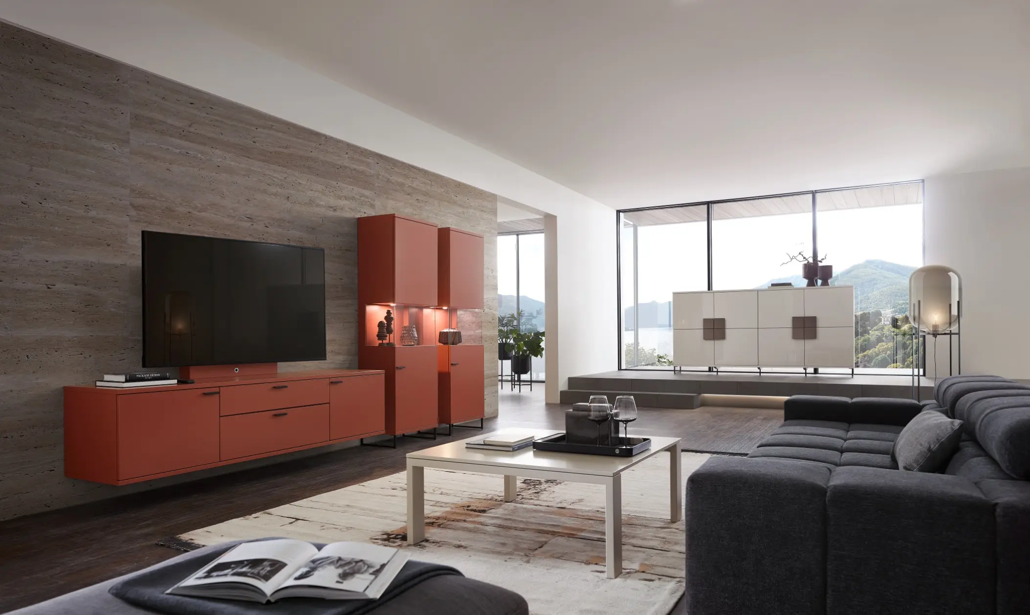 Wohnwand in rot mit hängendem Lowboard und beleuchteten Vitrinen im Wohnzimmer. Im Hintergrund passende helle Kommoden